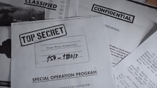 Slow Pan On Different Top Secret And Classified Documents And Memos On A Desk. Various Confidential Secretive Papers With Sensitive Information Of Investigation Or Espionage Piled Up In A Dark Office
