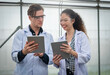 © nuttawutnuy - Portrait of Man and Woman agricultural researcher holding tablet while working on research at plantation in industrial greenhouse