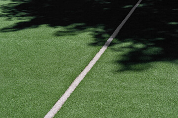 Wall Mural - Green synthetic grass sports field with white line and shadows. Sports background for product display, banner, or mockup.