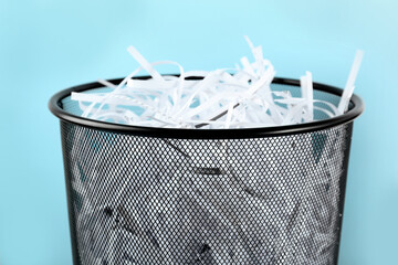 Wall Mural - Trash bin with shredded paper strips on light blue background