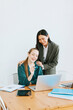 © klavdiyav - two young business women professionals in formal wear clothes work in modern office using laptop, tablet, brainstorm and search for solutions together, confident independent Asian girl solves problems