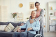© Mediaphotos - Portrait of content attractive wife in eyeglasses embracing husband in wheelchair around neck while helping him in recovery