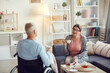 © Mediaphotos - Content senior woman in homewear sitting on sofa and drinking tea while smiling at handicapped husband during communication