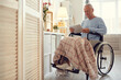 © Mediaphotos - Serious concentrated disabled senior man with paralyzed legs sitting in wheelchair and reading online article on tablet