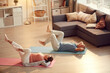 © Mediaphotos - Healthy senior couple lying on mats in living room and rotating legs while doing exercise for knee joints
