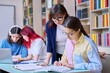 © Valerii Honcharuk - Group of teenage students and teacher study at desk in library