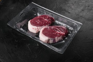 Wall Mural - Raw beef steak in vacuum package, on black dark stone table background, with copy space for text