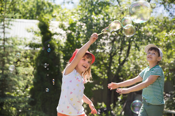 kids blows bubbles in a summer park. children friends have fun summer holidays in nature. happy and healthy childhood