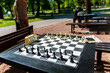 Chess board with pieces and clock on desk in connection with the chess tournament. Chess pieces and stopwatch on a board in the park.