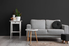 Interior Of Living Room With Grey Sofa, Table And Pouf Near Black Wall