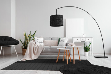 Interior of light living room with grey sofa, black lamp and carpet