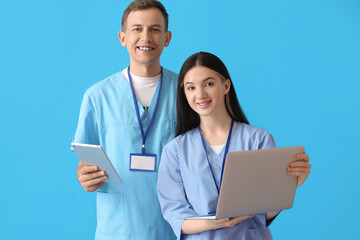 Wall Mural - Medical assistants with laptop and tablet computer on blue background