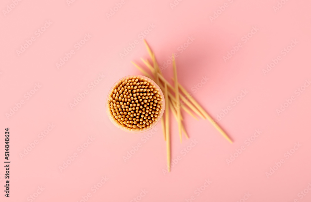 Box with wooden toothpicks on pink background