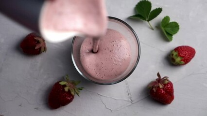 Wall Mural - Pouring strawberry smoothie with protein into glass.