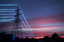 Electricity Transmission Towers With Glowing Wires Against The Sunset Sky Background.