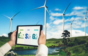 Green business transformation for environment saving and ESG business concept. Businessman using tablet to set corporate goal toward environmental friendly management and alternative clean energy use.