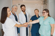 © Kostiantyn - Group of professional medical team of doctors putting their hands together