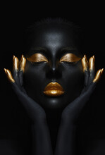 Beauty Woman Painted In Black Skin Color Body Art, Gold Makeup Lips Eyelids, Fingertips Nails In Gold Color Paint. Professional Gold Makeup