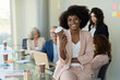 © Westend61 - Smiling businesswoman holding disposable cup sitting on table at office