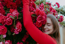 Happy Woman With Eyes Closed Embracing Rose Plant