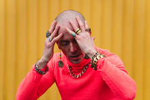 Mature Bald Man With Hands On Head In Front Of Yellow Wall