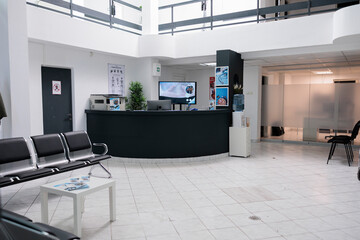 Wall Mural - No people in waiting area for patients with doctor appointments in modern healthcare clinic in private practice hopital. Empty waiting room with front desk reception with promotional flyers.