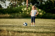 © Westend61 - Girl standing with hand on hip by soccer ball at sports field