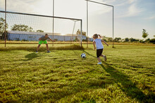 Girl Kicking Soccer Ball In Front Of Father Defending At Sports Field