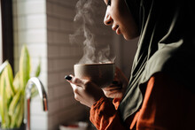 Young Calm Woman In Hijab Holding Cup Of Hot Tea