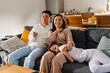 Happy smiling asian family sitting on sofa watching tv