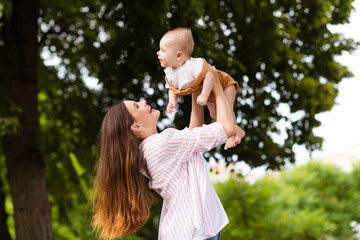 Canvas Print - Photo of excited cheerful mother little son dressed casual clothes rising arms enjoying sunshine outdoors backyard