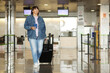 © Andriy Medvediuk - middle aged woman traveling in casual clothes. Female in airport with suitcase and passport going after check-in desk in for her flight. Passenger travel abroad on holiday or weekend.