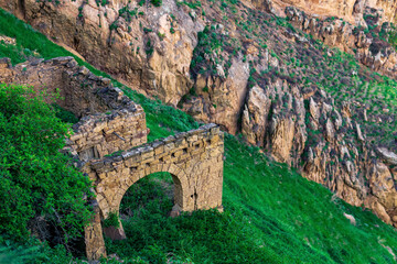 Wall Mural - ruins of stone walls on a steep mountain slope in an abandoned highlanders village Gamsutl in Dagestan