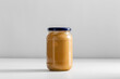 food storage, eating and preserve concept - close up of jar with canned vegetable puree or peanut butter on table
