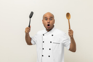 Young handsome asian man chef in uniform holding turner and ladle utensils cooking in the kitchen various gesture action on isolated background. Indian man Occupation chef restaurant and hotel.