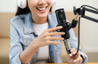 © Chanakon - Content creator woman host streaming her a podcast on laptop with headphones and microphone interview cheering guest conversation at broadcast studio. Blogger motivation recording voice over radio.