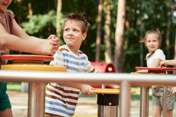 Wall Mural - Little boy with friends playing at the playground in summer day