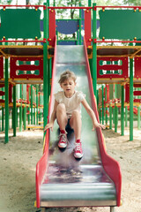 Wall Mural - Caucasian girl playing at sliding in summer day