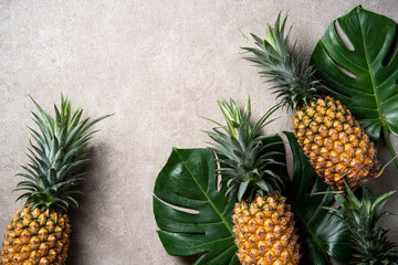 Wall Mural - Fresh pineapple with tropical leaves on gray background.