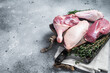 Butchered whole duck, raw breast steak, legs, wings on a butcher cutting board. Gray background. Top view. Copy space