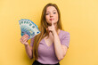 © Asier - Young caucasian woman holding banknotes isolated on yellow background keeping a secret or asking for silence.