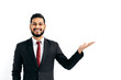 © Kateryna - Copy-space for your presentation. Positive elegant arabian or indian man in formal suit, standing over isolated white background, looking at camera, pointing hand to empty space, smiles happily