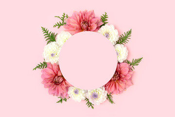 Wall Mural - wreath made of dahlia and green leaves on a pink background. flower round frame with copyspace.
