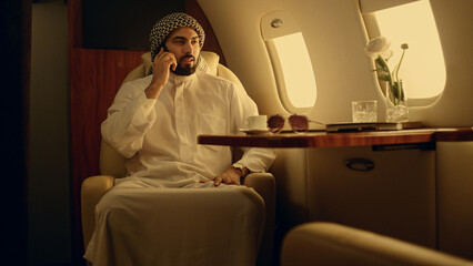 Wall Mural - Professional speaking mobile phone in private jet. Businessman discussing work