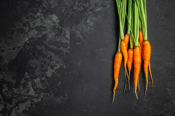 Wall Mural - Fresh and sweet carrot bunch on dark background. Healthy vegan vegetable food. banner, menu, recipe place for text, top view