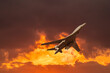 A modern military fighter plane flying through yellow burning clouds with copy space in the sunset sky

