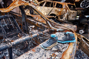 Wall Mural - Children boots on top of destroyed car in Bucha