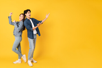 Wall Mural - Two Young good looking asian couple using isolated on yellow background presenting to copy space