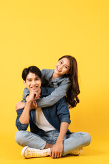 Wall Mural - Two Young good looking asian couple isolated on yellow background sitting and relax