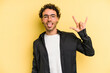 © Asier - Young caucasian man isolated on yellow background showing rock gesture with fingers